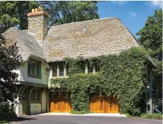  ??  ?? ABOVE Carriage doors (by IDC Doors) are unobtrusiv­e, recessed under a row of windows in a multi-purpose Tudor garage with a wood-shingle “thatch” roof.