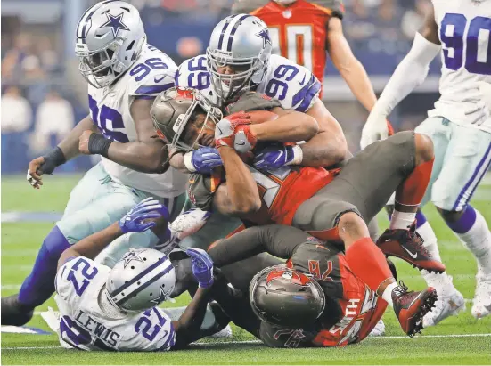  ?? RON JENKINS/AP ?? Buccaneers running back Jacquizz Rodgers is stopped on a run by Cowboys cornerback Jourdan Lewis (27) and defensive tackle Antwaun Woods (99) in the first half Dec. 23 in Arlington, Texas.