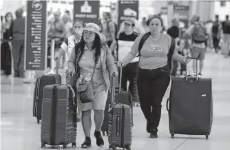  ?? Marta Lavandier/Associated Press ?? Travelers walk to check in their bags Saturday at Miami Internatio­nal Airport. Passenger numbers at U.S. airports Friday were 13 percent higher than on July 1 last year.