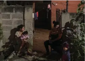  ?? AP ?? Una familia aguardaba fuera de su casa mientras expertos de la Policía buscaban evidencias de un asesinato en San Pedro Sula.