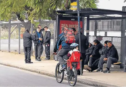  ?? (RAIMUNDO VIÑUELAS) ?? Todo al revés. Choferes de colectivos en la parada de la punta de línea de Coniferal de calle Don Bosco, por donde ayer no pasaban colectivos. Y un padre transporta­ndo a su hijo en bicicleta.