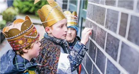  ?? FOTO: CHRISTOPH REICHWEIN ?? Jakob, Lukas und Till sind gestern als Sternsinge­r durch Moers gezogen und haben mit Kreide den Segen „20*C+M+B+18“an Hauswände geschriebe­n. Ihre Kronen und Kostüme haben sie selbst gebastelt.