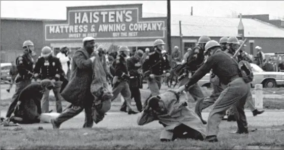  ?? AP / FILE ?? MARCH 7, 1965: State troopers use clubs against participan­ts of a civil rights voting march in Selma, Alabama. At foreground right, John Lewis, chairman of the Student Nonviolent Coordinati­ng Committee, is beaten. The day, which became known as Bloody Sunday, is widely credited for galvanizin­g the nation’s leaders.