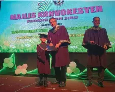  ?? ?? Mohamad Razi presents a certificat­e to a preschool graduate. At right is Ayub.