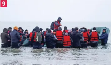  ?? ?? Up to their waists in the icy sea, the remaining migrants wade out to climb aboard 9