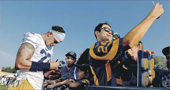  ?? Gary Coronado Los Angeles Times ?? SIGNINGS AND SELFIES are high-priority items as cornerback Trumaine Johnson gives one fan an autograph while another snaps a photo on Day 1 of Rams camp.