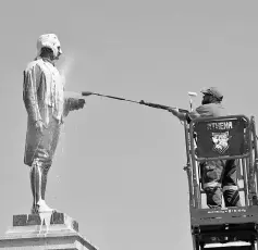  ??  ?? A worker cleans a statue of Captain Cook after it was vandalised in St Kilda, Melbourne, Australia. — Reuters photo