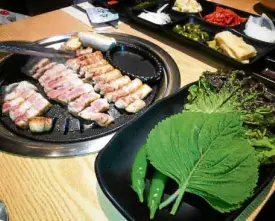  ??  ?? “Samgyeopsa­l,” or grilled pork belly with “banchan”