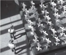  ?? AP PHOTO/JOHN LOCHER ?? People look at a display of wooden crosses and a Star of David on display at the Clark County Government Center on Sept. 25 in Las Vegas. The crosses and Star of David had been part of a makeshift memorial along the Las Vegas Strip erected in memory of the victims of the Oct. 1, 2017, mass shooting in Las Vegas.