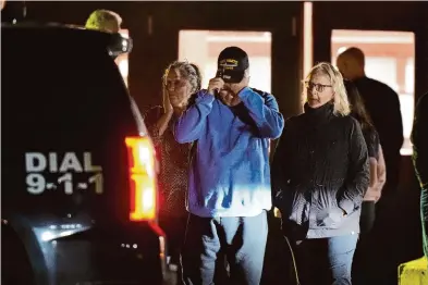  ?? Steven Senne/ Associated Press ?? People leave a reunificat­ion center early Thursday at Auburn Middle School in Auburn, Maine, after shootings in Lewiston left 18 dead and 13 injured. Authoritie­s were searching Thursday for the accused gunman.