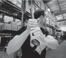  ?? Ted S. Warren, The Associated Press ?? Brent Weidenbach, the director of product management for Axe Bat, holds one of his company's baseball bats in the batting cage at the company's warehouse in Renton, Wash.