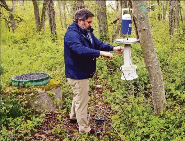  ?? Ned Gerard / Hearst Connecticu­t Media ?? John Shepard, from the Connecticu­t Agricultur­al Experiment Station, places a mosquito trap in a wildlife preserve in Milford.