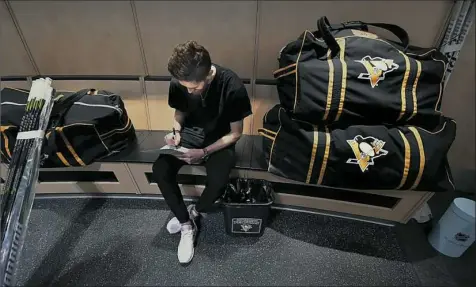  ?? Peter Diana/Post-Gazette ?? Matt Murray signs a stack of pictures Wednesday before departing the players’ room at the UPMC Lemieux Sports Complex in Cranberry.
