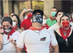  ?? ALVARO BARRIENTOS THE ASSOCIATED PRESS ?? Residents wear masks and kerchiefs as they march the route of the running of the bulls in Pamplona on June 20. This year’s San Fermin festival was cancelled.
