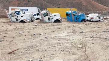  ?? Francine Orr Los Angeles Times ?? BIG RIG CABS peek out of the mud covering Highway 58 east of Tehachapi in Kern County, where vehicles were stranded overnight. In all, the storm left an estimated 300,000 cubic yards of debris on major roadways.