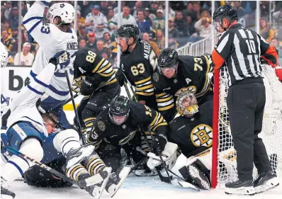  ?? MADDIE MEYER GETTY IMAGES ?? Bruins goalie Jeremy Swayman looks for the referee’s help as his crease is filled with teammates and Maple Leafs.