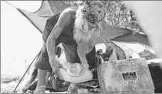  ?? ROSS D. FRANKLIN / AP ?? Roberto Delaney fills up a cup as his ice bag melts at a homeless encampment in Phoenix on July 19.