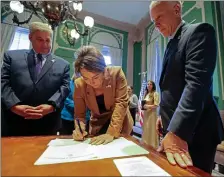  ?? STUART CAHILL — BOSTON HERALD ?? Gov. Maura Healey Signs the official papers to make Republican state Sen. Peter Durant’s victory official this past November.