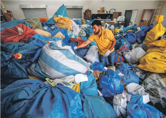  ?? AFP ?? A Palestinia­n postal worker sifts through sacks of mail withheld by Israel, for up to eight years, at the main post office in Jericho in the West Bank