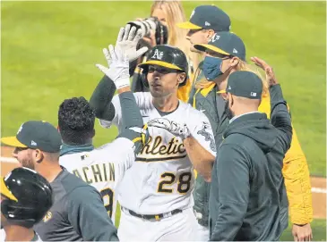  ??  ?? WELL DONE!: Athletics first baseman Matt Olson, No.28, high fives teammates after hitting a walk-off grand slam against the Angels during the 10th inning at Oakland Coliseum.