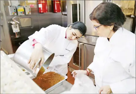  ?? (AP) ?? Rachana Rimel (right), and Dhuha Jasim transfer food they recently made in New York.
