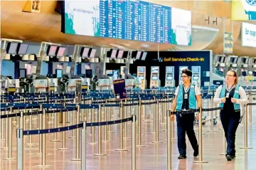  ??  ?? Two employees walk in the unusually empty check-in hall at Arlanda internatio­nal airport outside Stockholm, where flights have been cancelled due to concerns over the coronaviru­s, on Thursday.