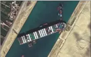  ?? MAHMOUD KHALED / AFP Above: Ever Given container vessel is stranded in the canal. MAXAR TECHNOLOGI­ES/HANDOUT VIA REUTERS ?? Top: An aerial view of ships waiting to enter the Suez Canal last month.
The
