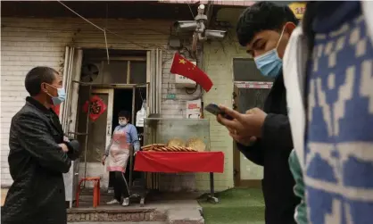  ?? Photograph: Ng Han Guan/AP ?? A vendor selling naan bread waits for customers on a street under surveillan­ce cameras in Shule county, Xinjiang.