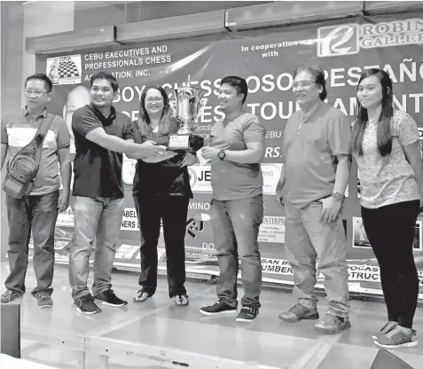  ??  ?? Edsel Montoya (third from right) is all smiles after receiving his championsh­ip trophy and cash prize during the awarding ceremony of the 27th CEPCA Anniversar­y Tournament-Boy 'Chessmoso' Pestaño Open Chess Memorial Cup last Sunday night at the Knight...