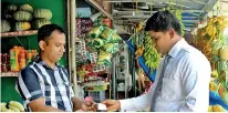  ??  ?? An LOLC Finance officer accepting cash from a customer and depositing it instantly through a POS machine