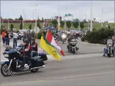  ?? ?? Ride captain Larry Carleton, carrying the Saskatchew­an flag on his bike, leads the start of the Ride for Dad parade in Swift Current, June 11.