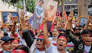  ?? | AFP ?? PROTESTERS hold images of detained civilian leader Aung San Suu Kyi and hold up three-finger salutes during a demonstrat­ion outside the Embassy of Myanmar in Bangkok yesterday, to mark the second anniversar­y of the coup in Myanmar.