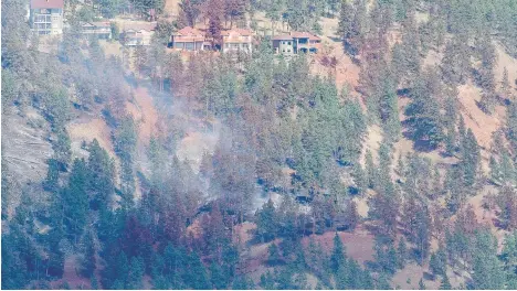  ?? JONATHAN HAYWARD/THE CANADIAN PRESS ?? Smoke and fire retardant are seen along a neighbourh­ood in Lake Country last Sunday. The RCMP believe that humans caused the blaze in the Okanagan region that engulfed eight homes and damaged 30 other properties.