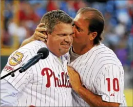  ?? THE ASSOCIATED PRESS FILE ?? Former Phils first baseman and current broadcaste­r John Kruk, left, is kissed by former teammate Darren Daulton during a ceremony to enshrine Kruk in the Phillies Wall of Fame before a game against the Washington Nationals Aug. 12, 2011 at Citizens...