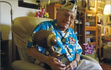  ?? ERIC RISBERG — THE ASSOCIATED PRESS ?? Mickey Ganitch, 101, holds a football trophy he received at his home in San Leandro last month. Ganitch had been preparing to play a game on Dec. 7, 1941. Instead, he spent the morning in his football uniform spotting planes for anti-aircraft gunners.