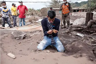  ?? AP Photo/Moisés Castillo ?? ■ Bryan Rivera cries as he looks at the remains of his house Thursday after his family went missing in the eruption of the Volcano of Fire in San Miguel Los Lotes, Guatemala. The country’s national disaster agency suspended search and rescue efforts at...