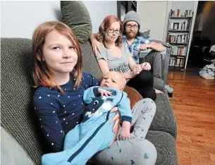  ?? JOHN RENNISON THE HAMILTON SPECTATOR ?? Julia, 9, holds her brother, Orion, with the company of their parents, Justine Taylor and Dan Weiss. The family is part of the province's basic income program, which is being cancelled.