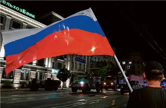  ?? AFP VIA GETTY IMAGES ?? A man waved a Russian national flag as Wagner group members prepared to return to their Rostov-on-Don base late Saturday.