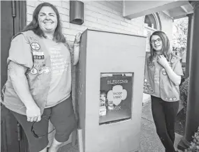  ?? ARIEL COBBERT/THE COMMERCIAL APPEAL ?? Girl Scout Troop leader Julie Tolbert and her daughter Jasmine Tolbert pose next to a green “Blessing Box” with canned goods at Masters Roofing in Bartlett, Tenn., on Saturday, November 7, 2020.