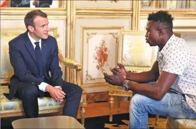  ?? THIBAULT CAMUS / AGENCE FRANCE-PRESSE ?? French President Emmanuel Macron speaks with Mamoudou Gassama, 22, from Mali, at the presidenti­al Elysee Palace in Paris, on Monday. Gassama was honored by Macron for scaling an apartment building at the weekend to save a 4-year-old child who was...