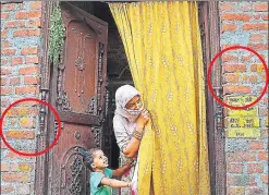  ?? SACHIN SAINI/HT PHOTO ?? (Above) A house in Bisauli with neem twigs over the door and turmeric on walls (in circle) to ward off the braid cutter. (Right) Children with alta (red colour) on their hands for protection, in Maujampur Bisauli village.