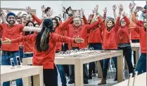  ?? MELANIE BELL / THE PALM BEACH POST ?? Employees show their enthusiasm during a warm-up session before the Apple store at The Gardens Mall reopened Saturday morning after eight months of remodeling.