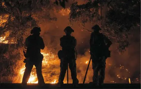  ?? Josh Edelson/AFP/Getty Images ?? Firefighte­rs watch a back burn during the Mendocino Complex fire Tuesday in Upper Lake, Calif.