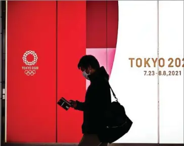  ?? AFP ?? A man walks along a corridor past an official Tokyo 2020 Summer Olympics advertisem­ent board in the Shinjuku district of Tokyo on November 30 last year.