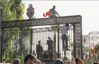  ?? Hedi Azouz / Associated Press ?? Tunisian soldiers guard the entrance to the parliament building as demonstrat­ors gather outside the gate in Tunis. The president suspended the legislatur­e after violent protests Sunday.