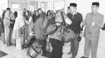  ??  ?? Rosey and Ripin (facing camera, fifth and second right) wishing all the pilgrims a smooth journey during the send-off at Miri Airport