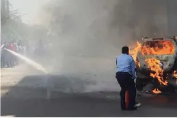  ?? — PTI ?? A private security guard tries to douse a fire which broke out in a moving car near MG Road Metro station in Gurgaon on Sunday.