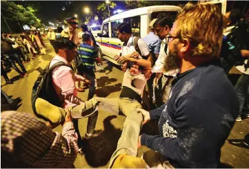  ?? — Reuters photo ?? People carry a man who was injured.