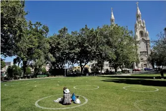  ?? AP PHOTO/JEFF CHIU ?? A woman and child sit in a circle designed to help prevent the spread of the coronaviru­s by encouragin­g social distancing at Washington Square park in front of Saints Peter and Paul Church in San Francisco on Saturday.