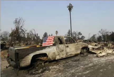  ?? JEFF CHIU — ASSOCIATED PRESS ?? A flag is draped across the back window of a burned truck Wednesday in Santa Rosa, Calif.